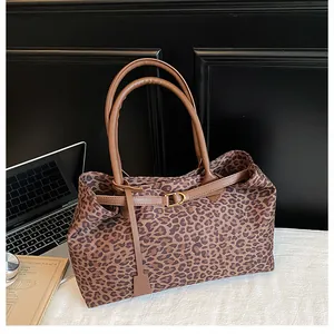 Detail shot of leopard print tote bag featuring a leather buckle strap and dual top handles
