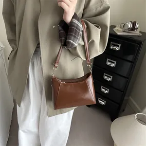Brown PU leather underarm bag with trapezoid design shown in a cozy home interior