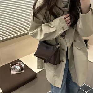 Brown leather crossbody bag with adjustable strap and gold metal buckle shown on model
