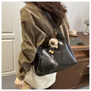 Detail of black leather tote bag with tassel zipper and cute plush alpaca pendant charm