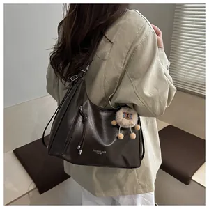 Detail view of large dark brown leather tote bag with stylish plush sheep charm
