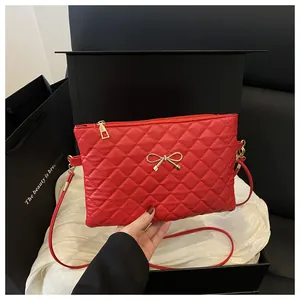 Detail of red quilted crossbody bag featuring a golden bow metal buckle on black background