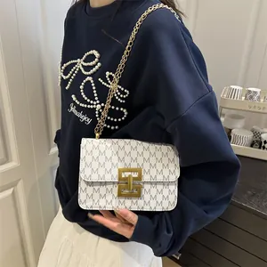 Petit sac carré blanc avec monogramme, bandoulière chaîne dorée et fermoir rotatif