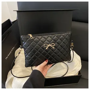 Detail of black quilted crossbody bag with a golden metal bow and elegant gift packaging