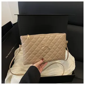 Close-up of beige quilted crossbody bag with golden bow detail in a premium black gift box