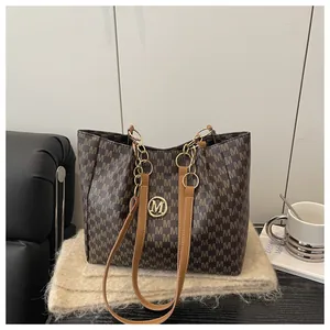 Détail du sac cabas marron à monogramme avec logo doré sur tissu tricoté beige