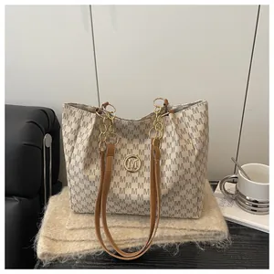 Gros plan sur un sac cabas élégant avec motif M gris foncé et logo en métal doré
