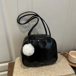 Borsa a spalla in vernice nera lucida con ciondolo in peluche bianco su fondo in maglia