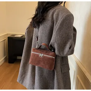 Détail d'un sac boîte marron mat avec doubles fermetures éclair argentées en forme de cœur