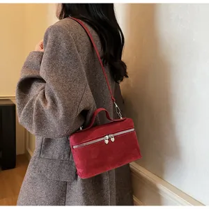Détail du sac boîte rouge avec zips en forme de cœur sur un mannequin en blazer gris