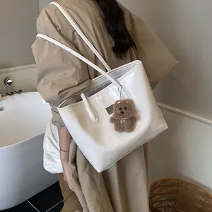Bolso tote minimalista de cuero brillante beige con colgante de oso de peluche marrón