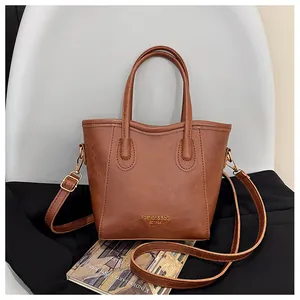 Detailed view of the brown leather bucket bag with textured finish and gold logo accents