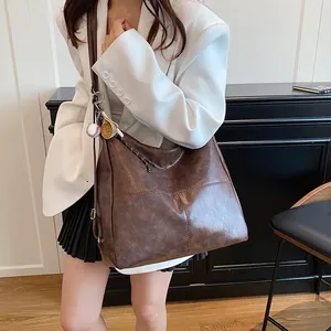Retro brown leather tote bag with baseball charm on a white blazer model outfit