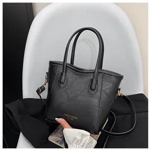 Detail of black leather bucket bag with gold logo on white chair for office styling