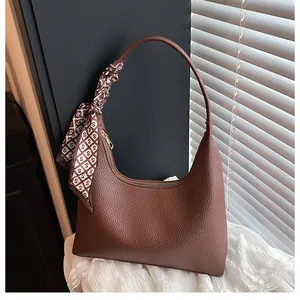 Détail du sac hobo en cuir grainé marron avec poignée ornée d'un foulard en soie