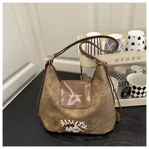 Close-up of vintage brown canvas bag featuring retro embroidery and leather strap