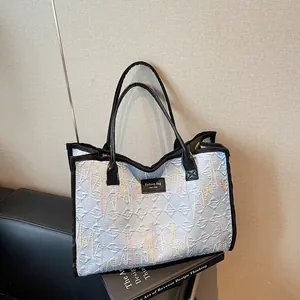Quilted light blue tote bag with colorful wave embroidery and black leather handles