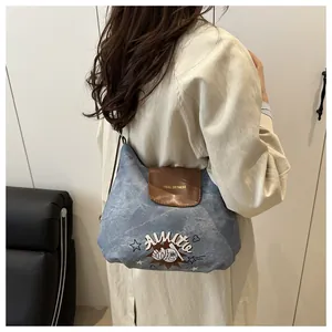 Detail of a chic denim and brown leather crossbody bag styled with a beige trench coat