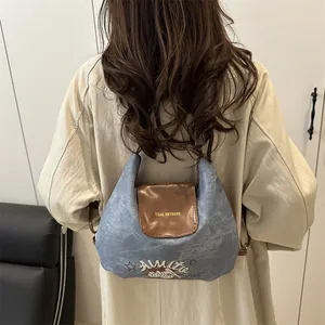 Vintage denim shoulder bag with brown leather flap and stylish embroidery shown on model