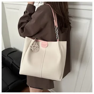 Detail view of large cream tote bag with pink trim and cute tiger leather pendant