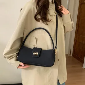 Schwarze Retro-Umhängetasche mit goldener Schnalle und Griff in einem Casual-Outfit