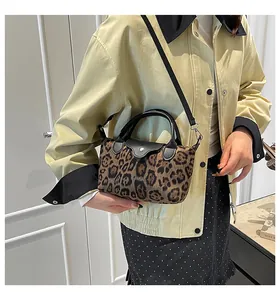 Detail of a leopard print handbag featuring black leather trim and silver metal buckle closure