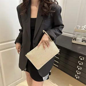 Chic vintage monogram envelope clutch bag with retro pattern held by model in casual style