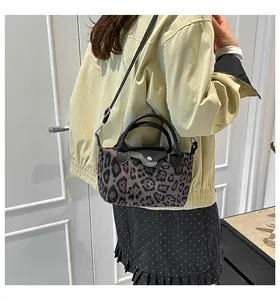 Detail view of the crossbody dumplings bag featuring grey leopard print and leather trim