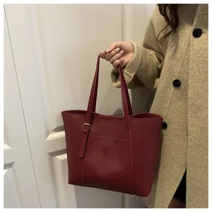 Détail du sac cabas en cuir bordeaux montrant la poche avant et la bandoulière réglable