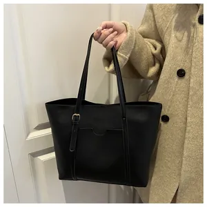 Détail du sac cabas en similicuir noir montrant les fines bretelles et la poche