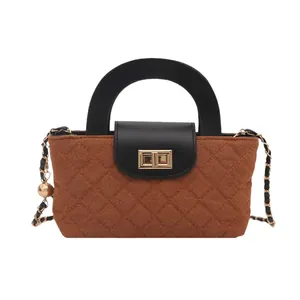 Brown quilted crossbody bag with black handle and gold chain strap on white background