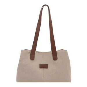 Minimalist beige canvas tote bag with brown leather handles and a centered decorative patch