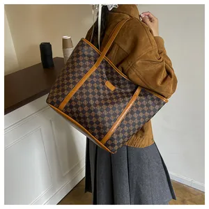 Detail view of large tote bag with brown checkerboard pattern shown on a model shoulder