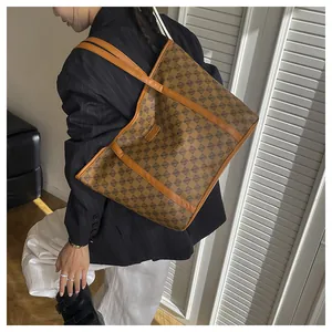 Detail of vintage tote bag featuring geometric patterns and brown leather trim on model