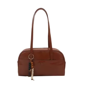 Brown retro bowling style shoulder bag in PU leather with beaded charm and front pocket