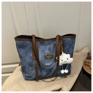 Detail der blauen Wash-Tote-Bag mit braunem Lederbesatz und süßem Wolken-Plüschanhänger