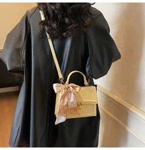 Detail of yellow square handbag with gold twist lock and elegant patterned silk scarf