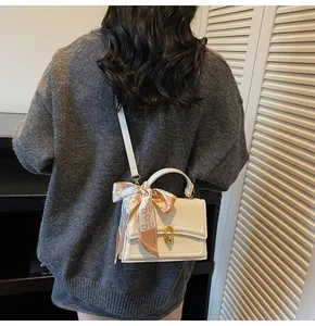 Detailed back side view of white crossbody bag with gold lock and silk scarf handle
