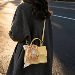 Chic cream leather crossbody bag with gold lock and silk scarf handle accent