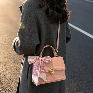 Pink crossbody handbag with gold clasp and silk scarf wrap on handle for women