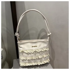 Detail of lace layers and JINGPIN logo on cream woven bucket bag with knot handle