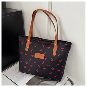 Detailansicht der schwarzen Kirsch-Tasche mit braunen Ledergriffen und Markenetikett