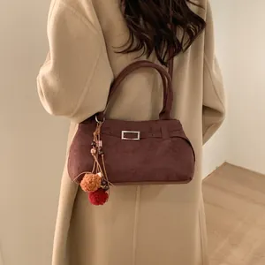 Retro burgundy suede tote bag with metal buckle and plush ball charm on camel coat