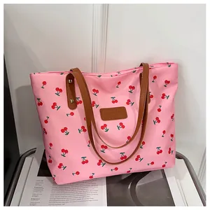 Detail der rosa Canvas-Einkaufstasche mit roten Kirschmotiven und braunen Ledergriffen