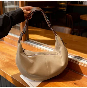 Dettaglio borsa tote in pelle scamosciata kaki con tracolla in pelle marrone su legno