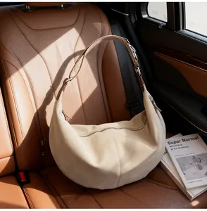 Dettaglio della borsa hobo in camoscio beige con tracolla in pelle su interni auto
