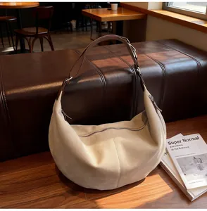 Dettaglio della borsa hobo in pelle scamosciata beige con tracolla su panca