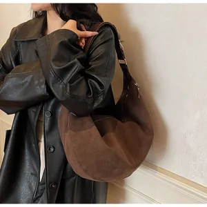 Dettaglio della borsa hobo in pelle scamosciata marrone opaca con cappotto