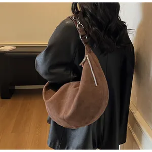 Borsa hobo marrone scamosciata indossata dal modello con dettagli di cerniera in argento