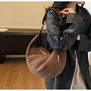 Dettaglio della borsa hobo in pelle scamosciata marrone scuro con cerniera argentata sulla spalla